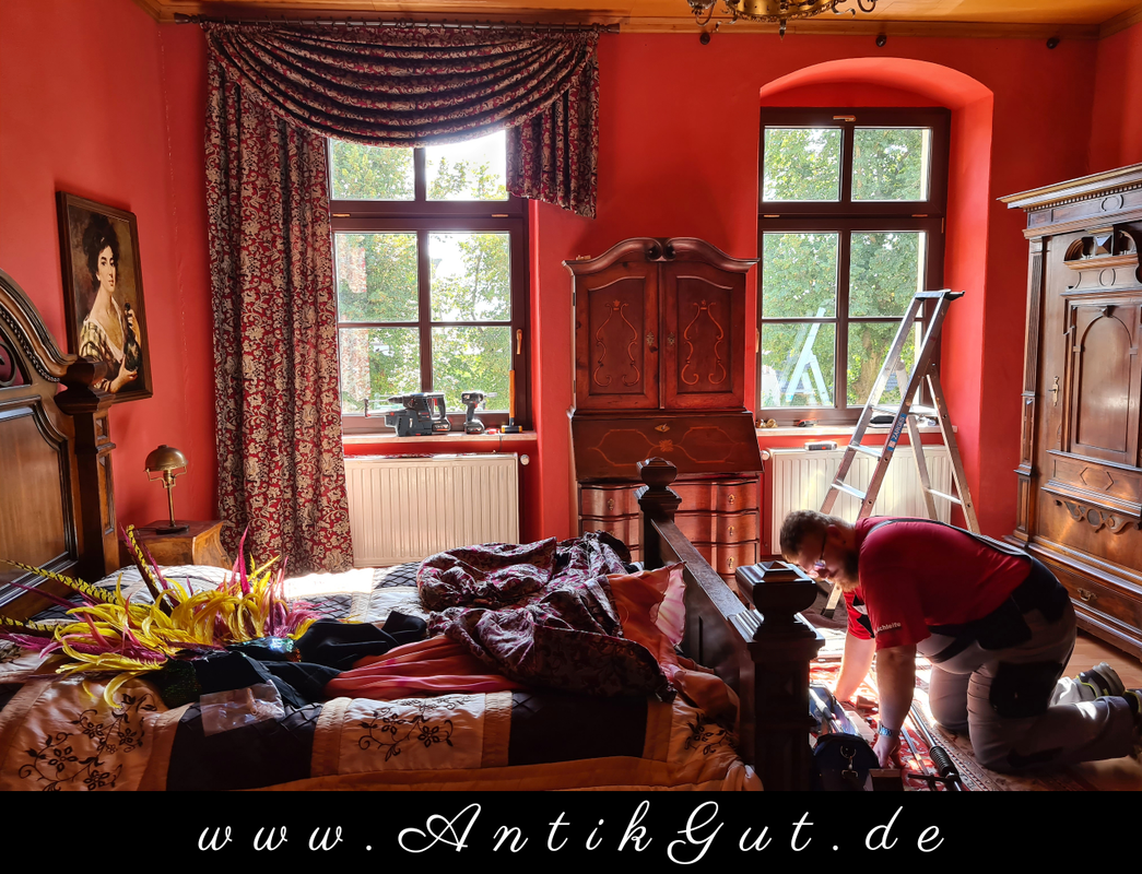 Der Innenausstatter hilft bei der Montage der Fensterdekoration im Gästezimmer vom Gutshaus Pöthen das AntikGut.
